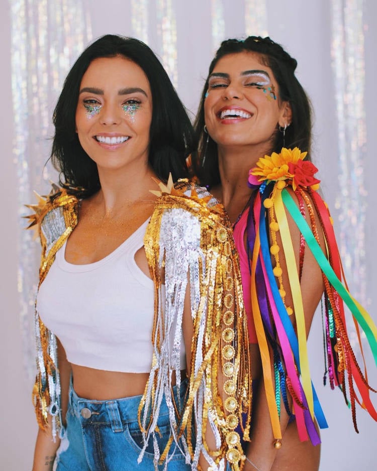 Duas mulheres usando ombreira colorida de carnaval.