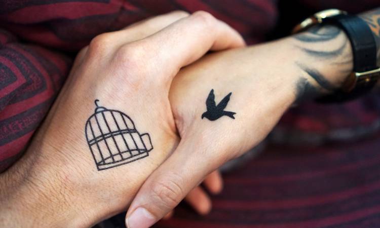 Casal em relacionamento aberto com tatuagem de gaiola e pássaro solto.