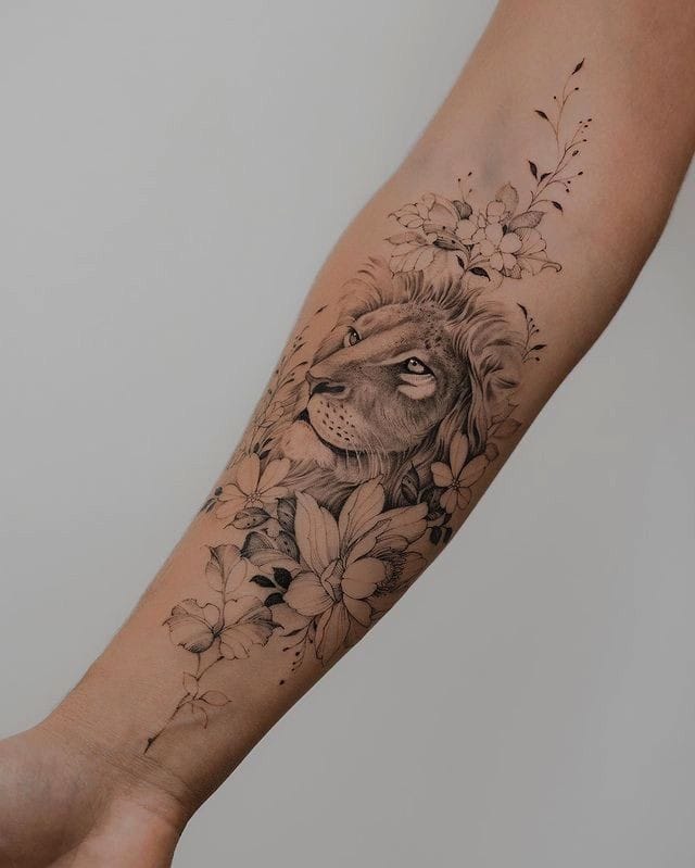 tatuagem no antebraço, rosto de um leão rodeado de flores
