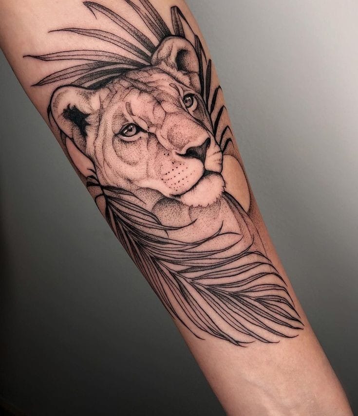 Tatuagem de leoa no antebraço, ao redor folhas