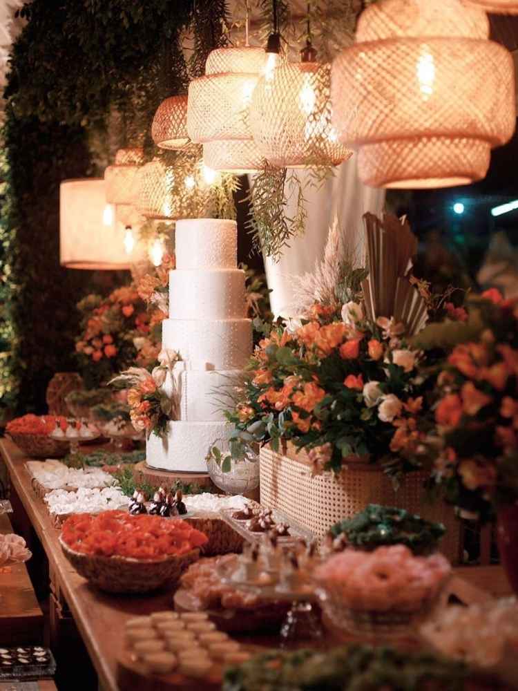 Decoração de casamento mesa de bolo com flores cor de laranja e doces.