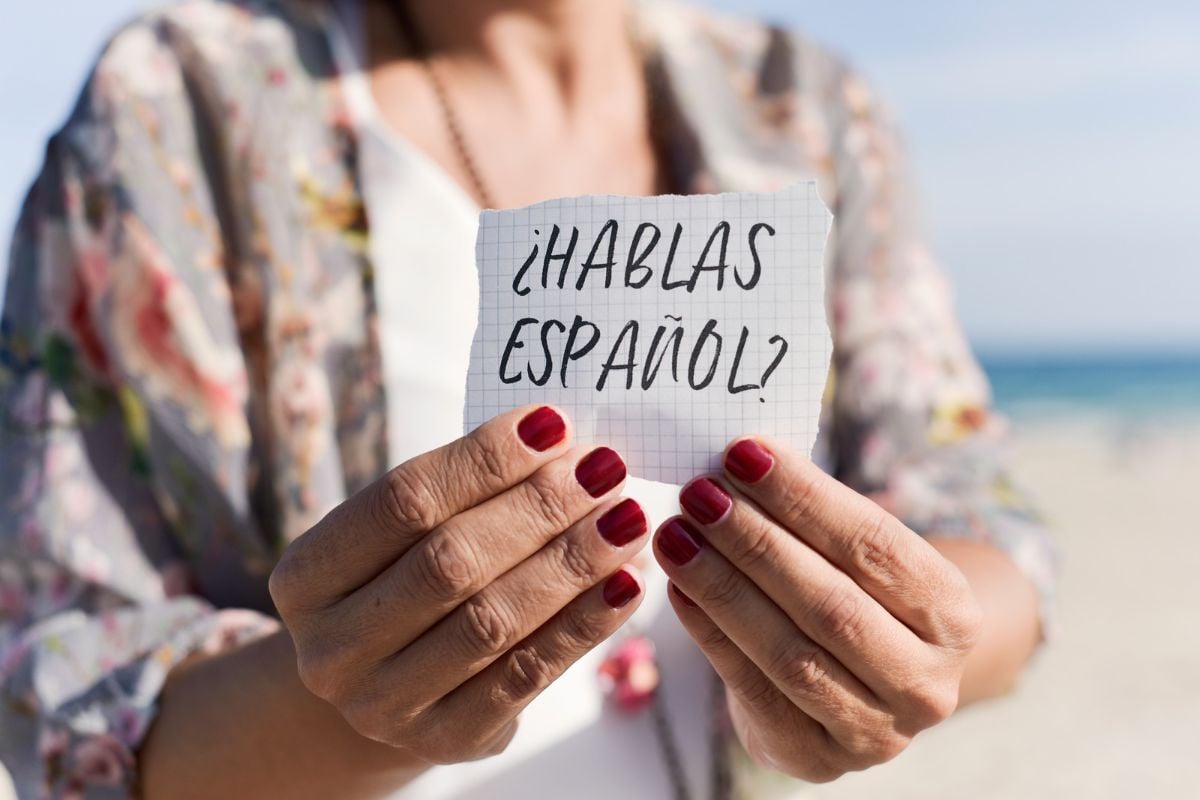 mulher segurando papel onde se lê o texto em espanhol hablas español