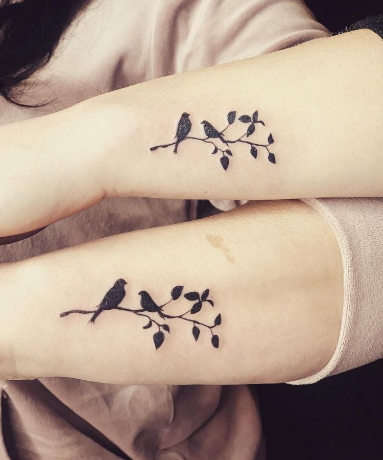 tatuagem mãe e filha no braço, de passarinhos em um galho de árvore