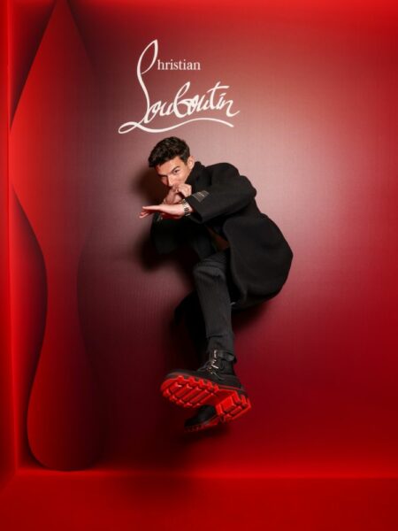 Paul Forman em fundo vermelho com jaqueta e calça preta, bota nos pés
