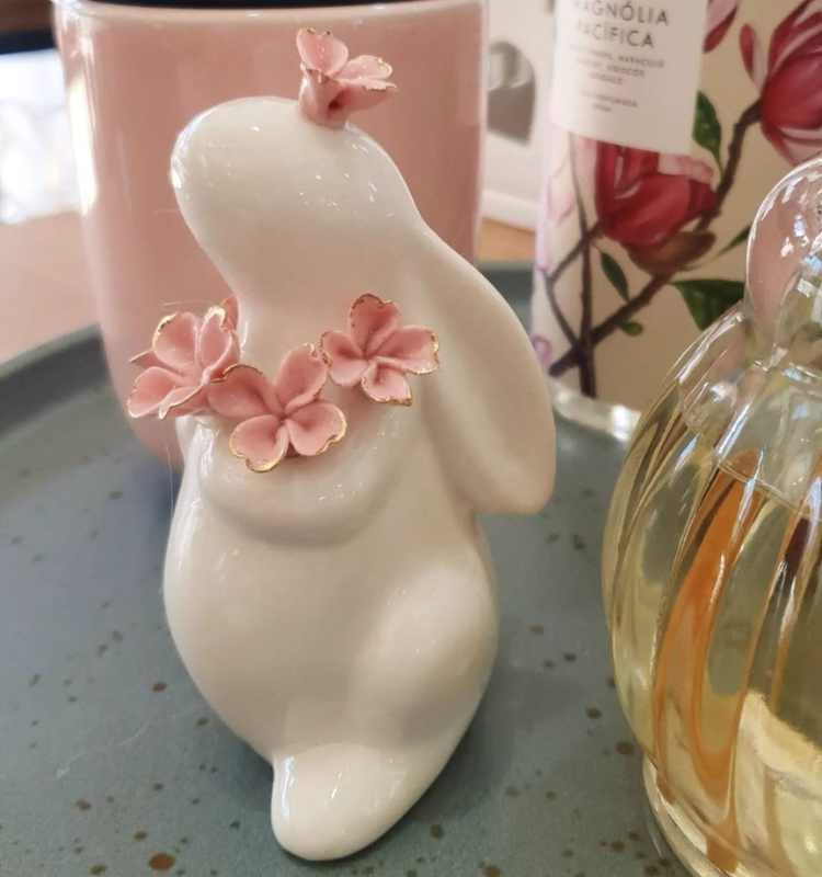 Coelha de cerâmica branca com flores cor-de-rosa.