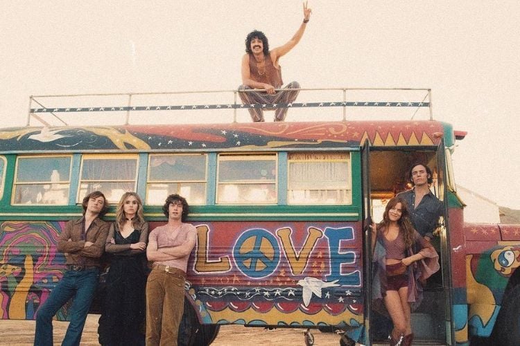 elenco da série posando em frente a um ônibus colorido, com desenhos e a palavras "love" na lateral. 