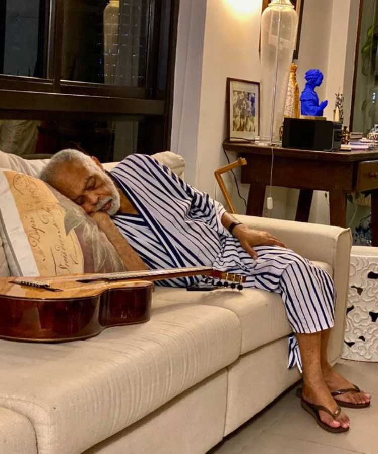 Gilberto Gil dormindo no sofá ao lado de violão;