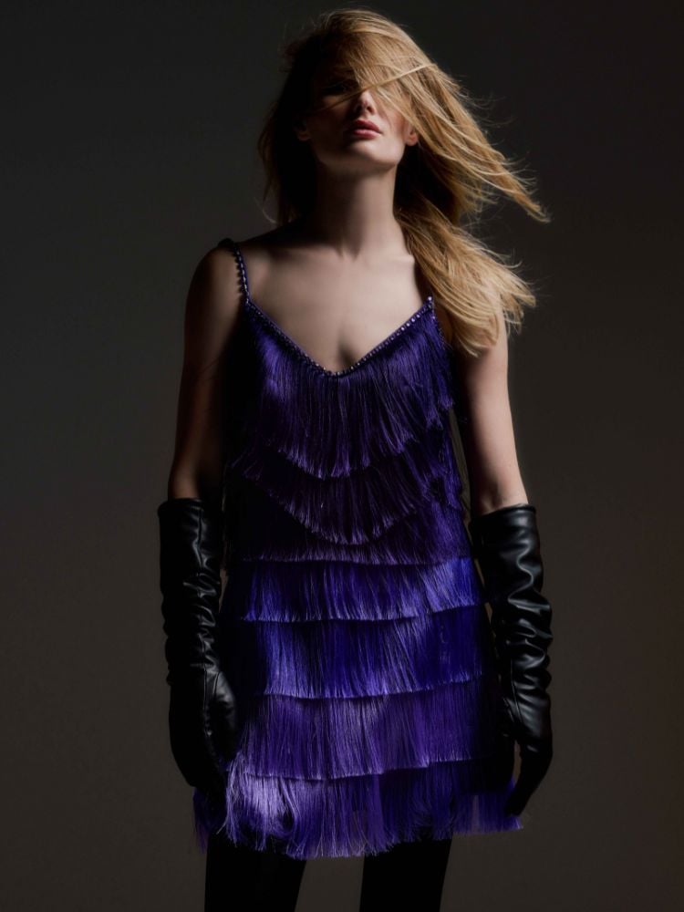 foto de modelo utilizando vestido roxo com franjas e luvas de couro. 