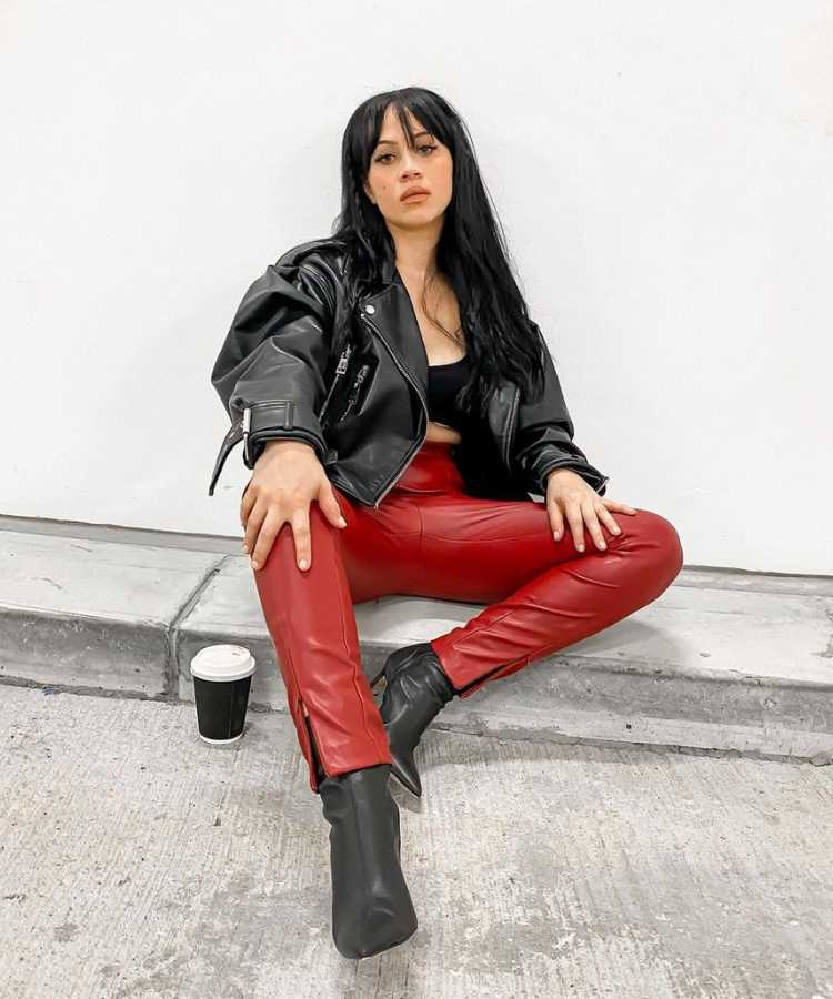 Mulher com looks tendência para Outono Inverno 2024: jaqueta de couro preta + calça de couro vermelha + bota de couro preta