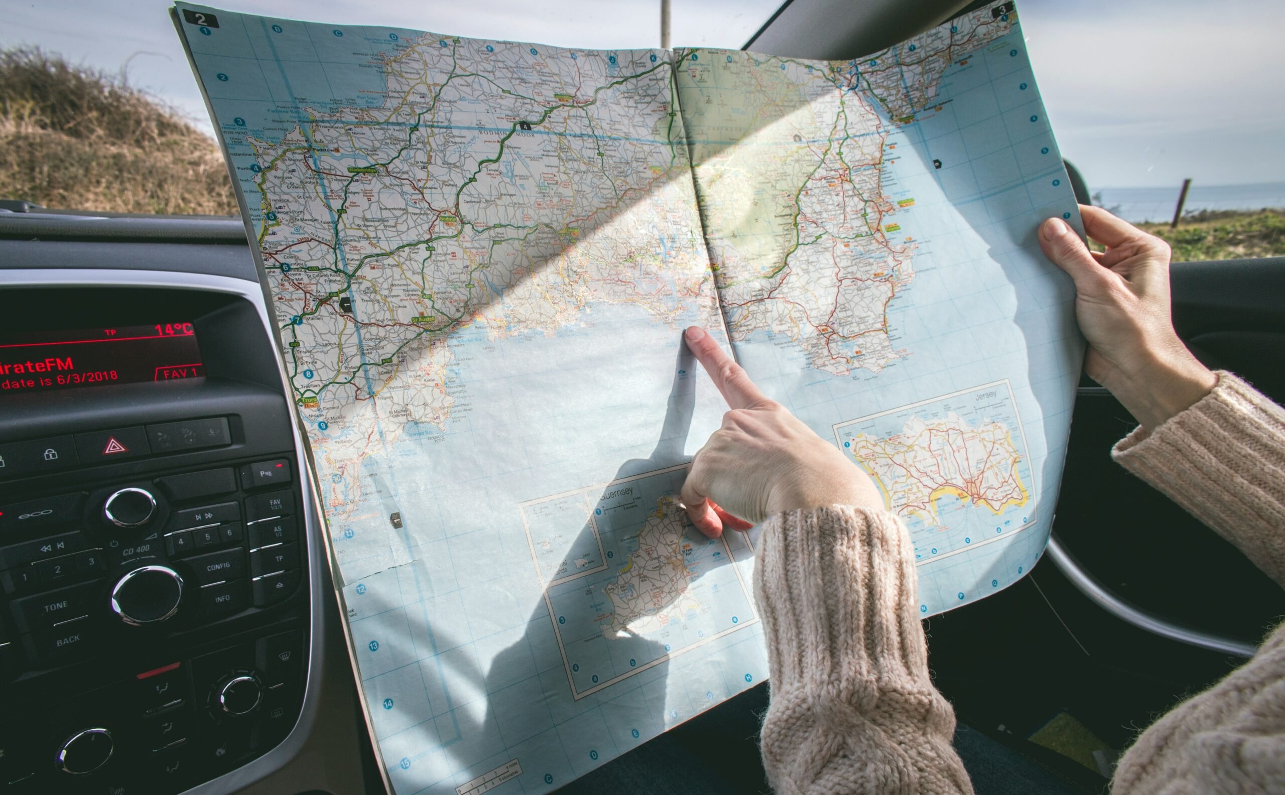 mão feminina apontando um mapa dentro do carro para representar o passeio turístico para casa signo