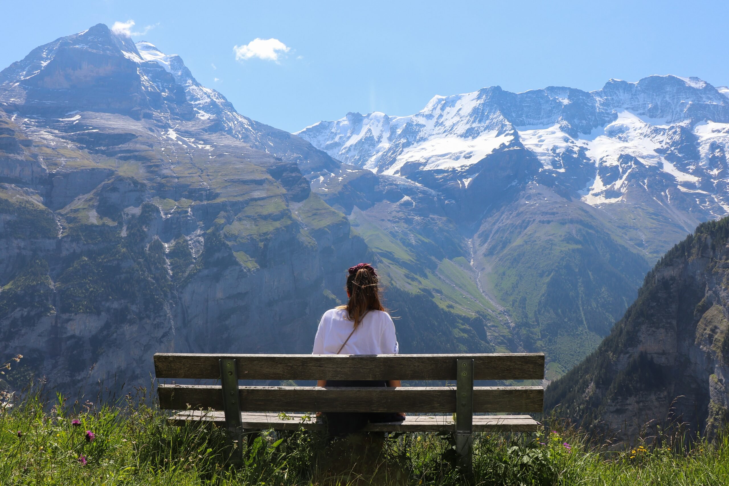 mulher em um banco olhando os Alpes Suíços em um dia de neve e Sol
