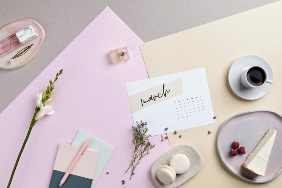 mesa com doces, canetas, papéis e um calendário do mês de março, quando começa o ano novo astrológico