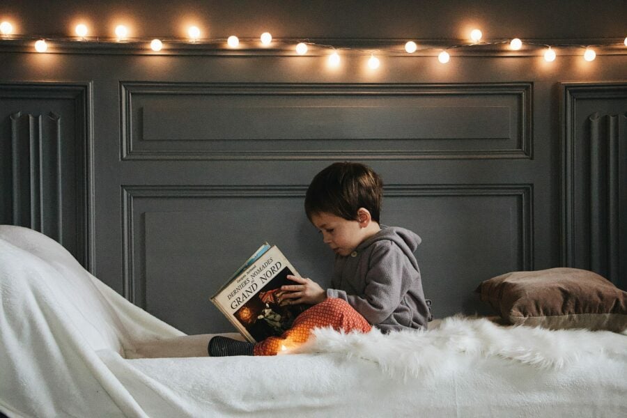 criança lendo um livro em um lugar confortável e iluminado