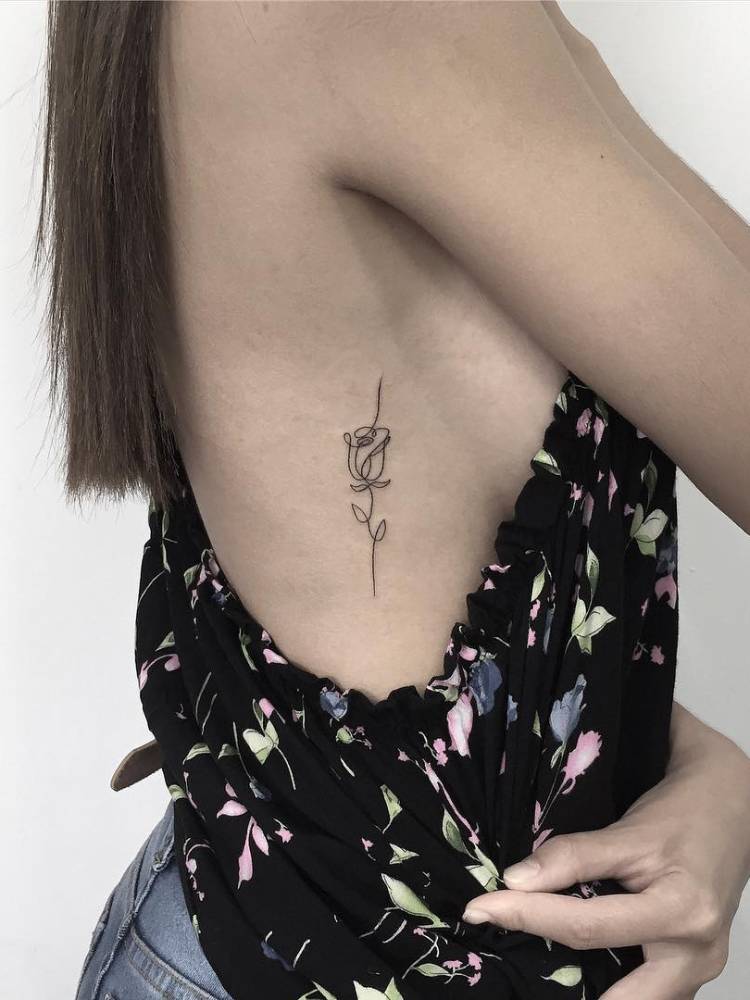 Tatuagem feminina na costela, de uma rosa com traço contínuo