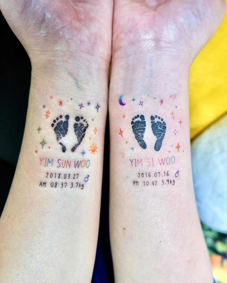 tatuagem nos dois pulsos, cada braço com uma data de nascimento diferente e pés de recém nascido, decorações de brilho ao redor