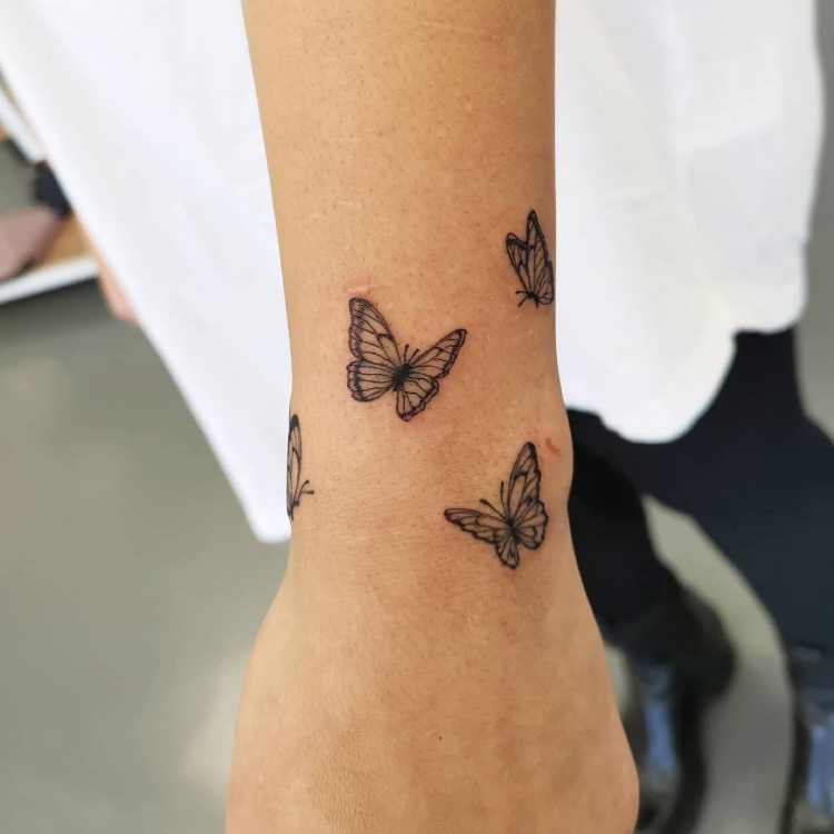 tatuagem no pulso com borboletas pequenas ao redor da região