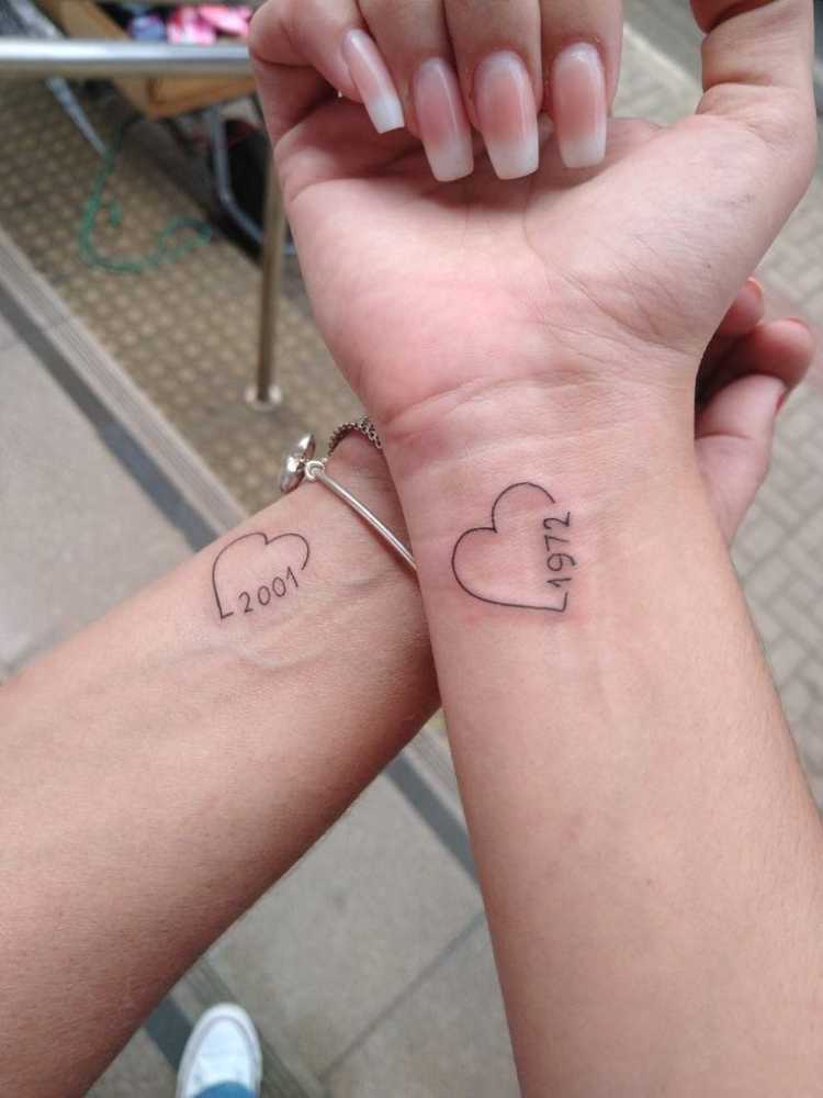 dois braços com tatuagem de coração, ano na borda