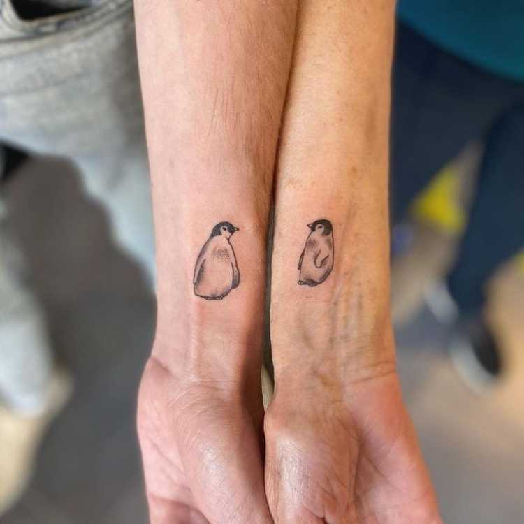 tatuagem mãe e filho no braço, cada um com um pinguim 