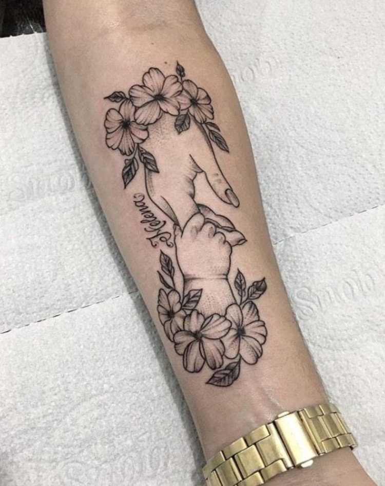 tatuagem mãe segurando mão recém-nascido, flores ao redor