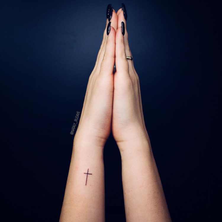 mão em modo de oração e tatuagem de cruz no pulso, parte lateral