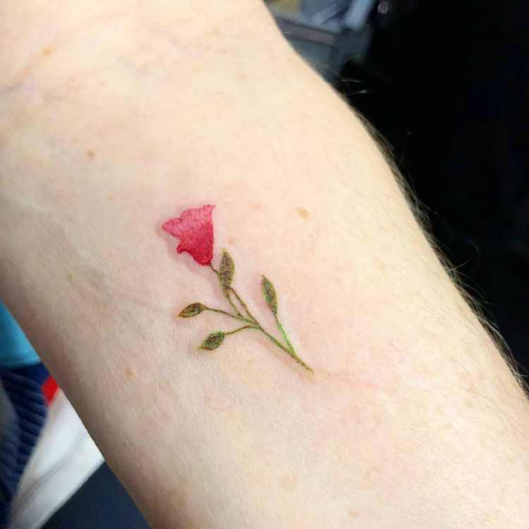 tatuagem de flor vermelha no pulso