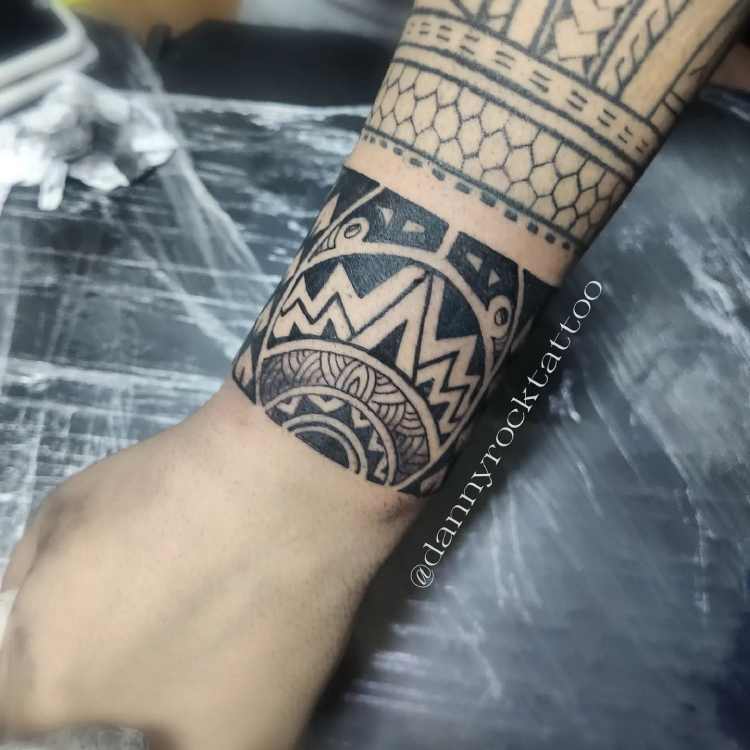 braço com tatuagem estilo tribal no pulso todo ao redor