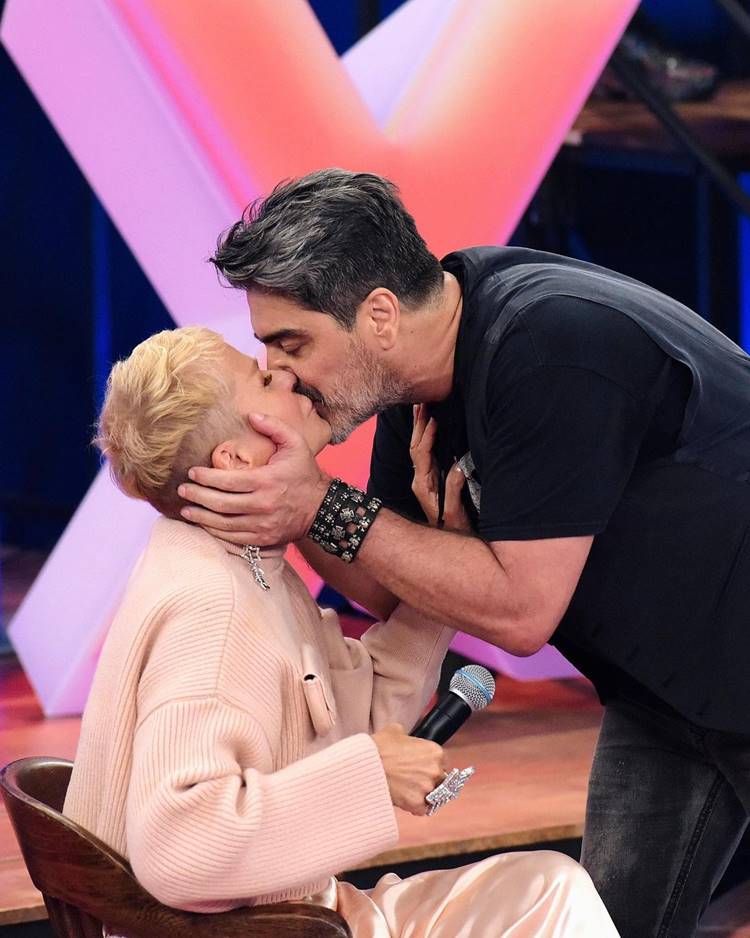 Xuxa e seu namorado, Junno Andrade, se beijando em programa de TV.