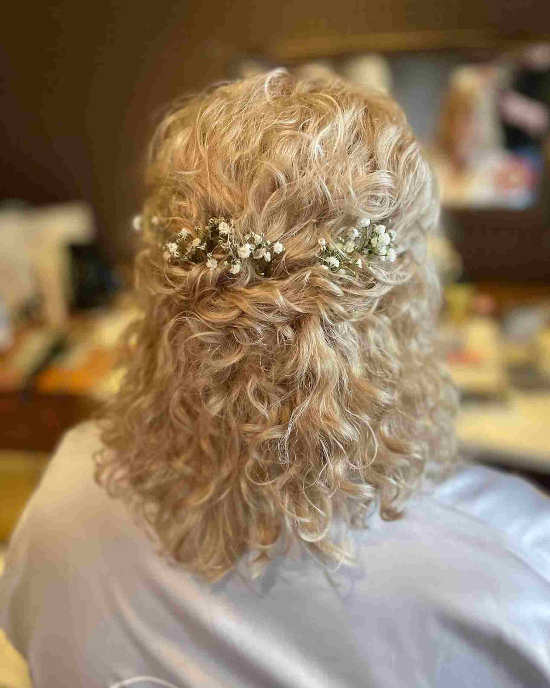 mulher loira de cabelo curto de costas, detalhe de raminhos no cabelo
