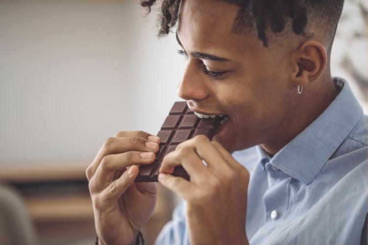 homem comendo barra de chocolate.