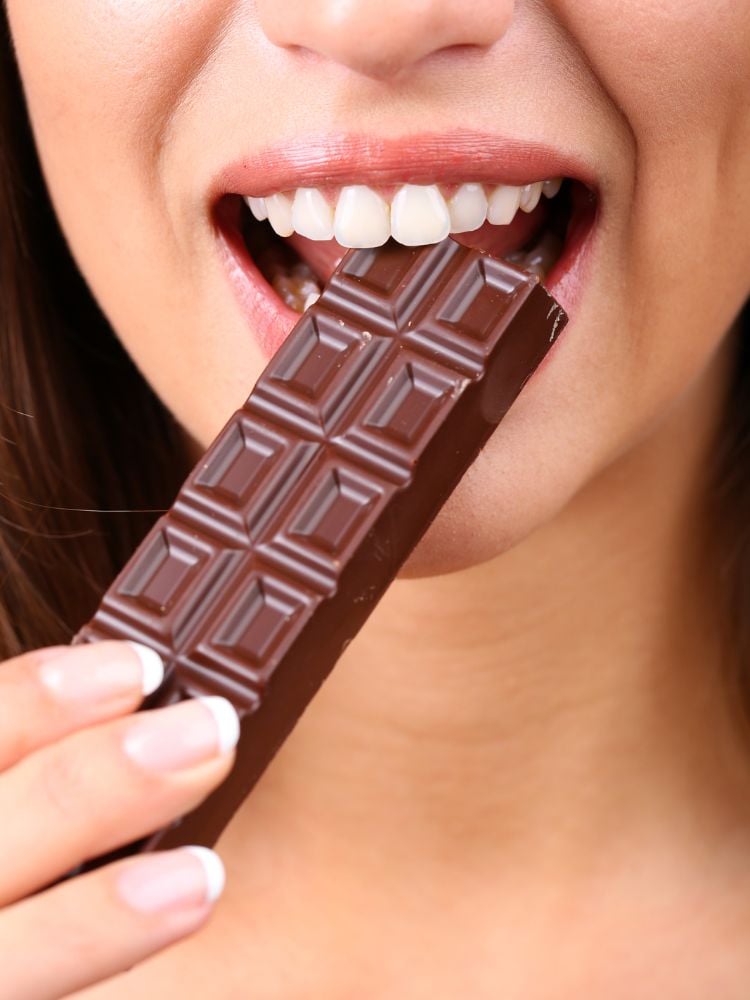 mulher comendo barra de chocolate. 