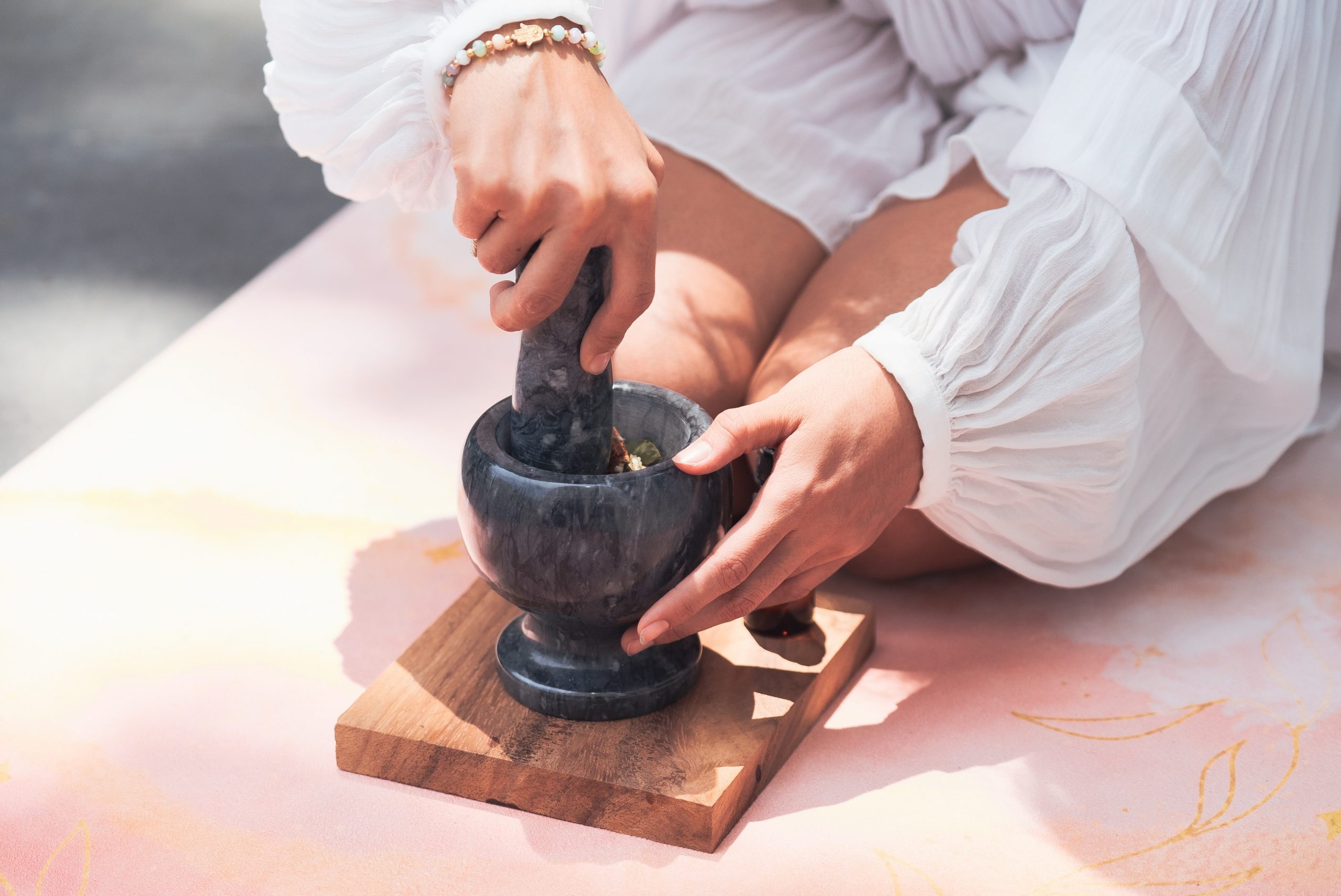 mãos femininas macerando ervas