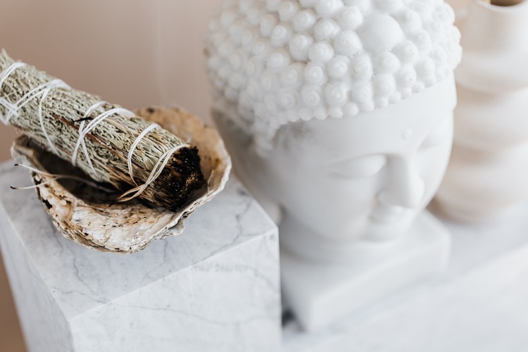 incenso natural de sálvia aceso do lado de uma estátua budista