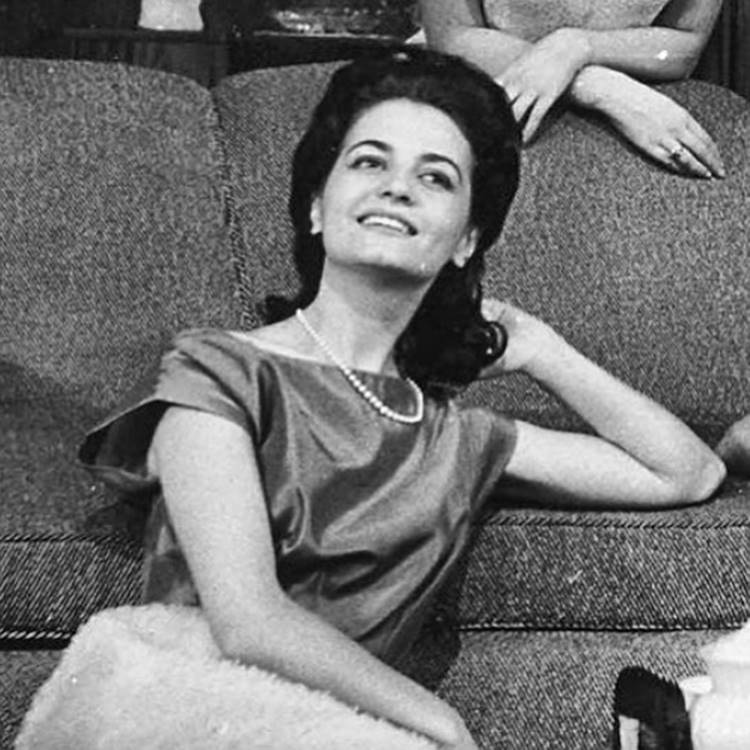 A atriz em foto antiga em preto e branco sentada no chão de frente para um sufá.