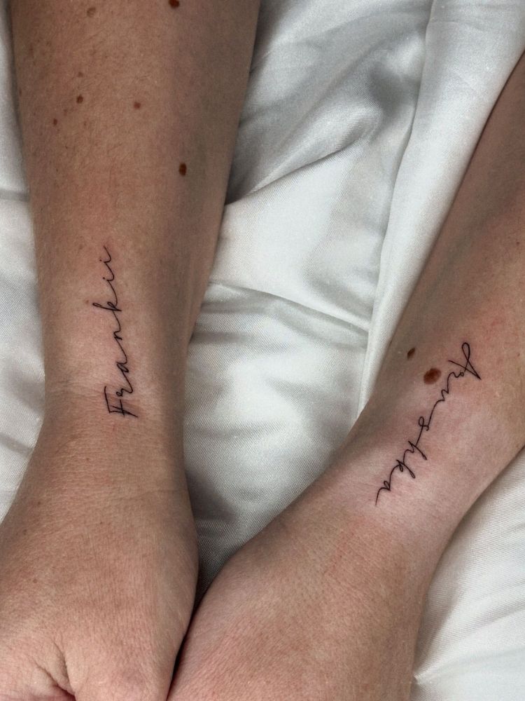 Pulsos de pessoa de pele clara cada um com uma palavra tatuada na lateral