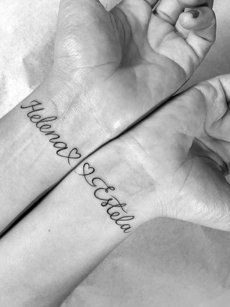 Foto em preto e branco de pulsos unidos, com nomes "Helena" e "Estela" tatuados em letra cursiva