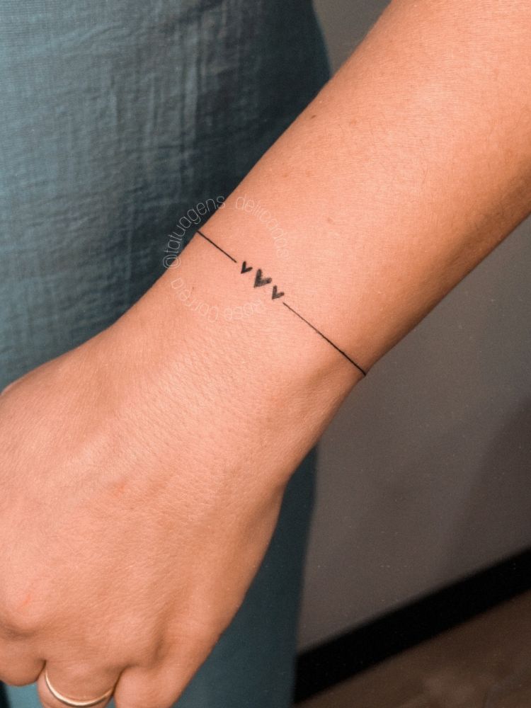 Pulso tatuado com linha fina e 3 corações