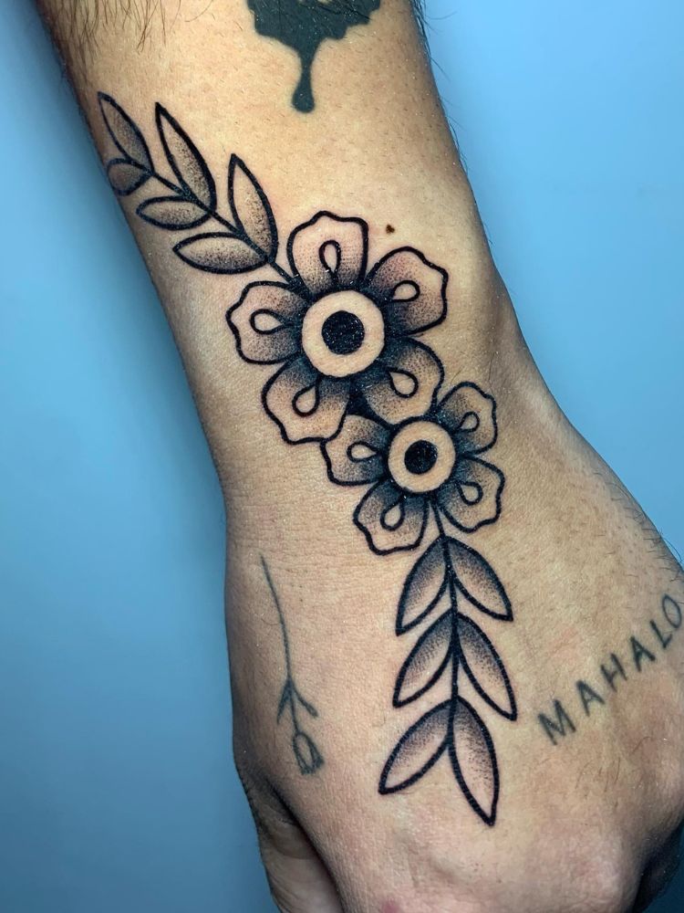 Pulso de pessoa de pele clara com flor old school e escrito na mão