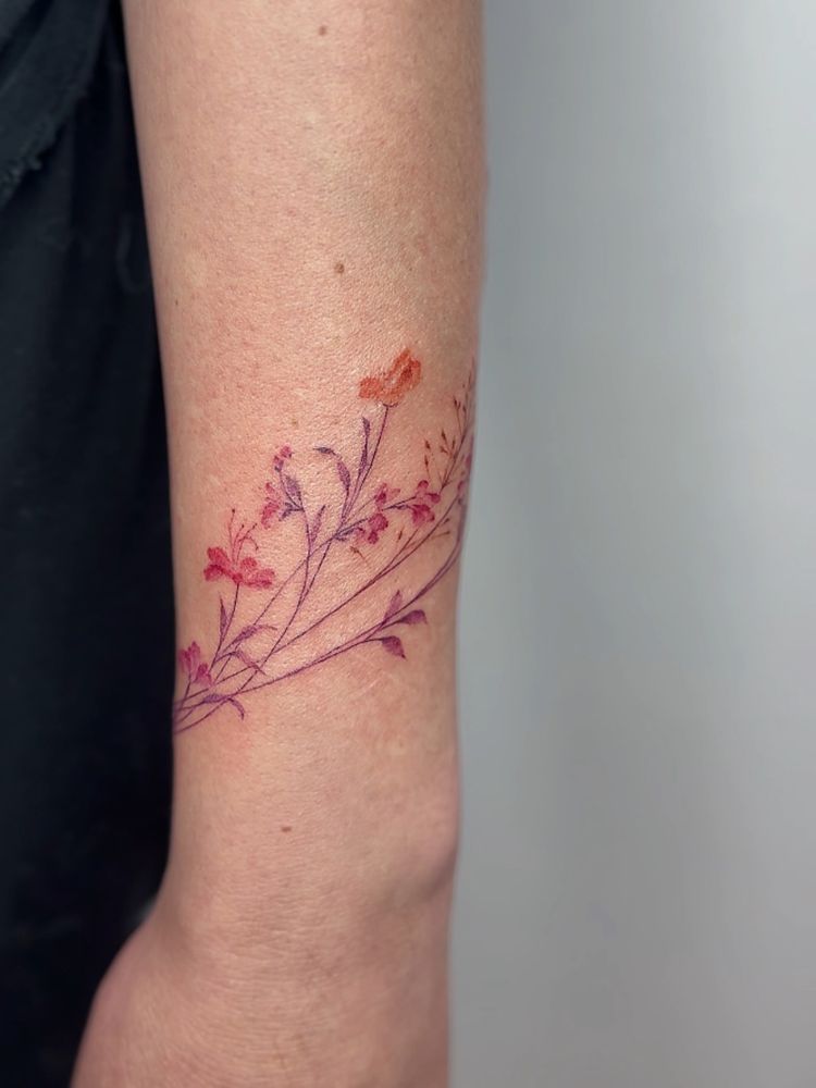 Pulso de pessoa de pele clara com flores em rosa e lilás