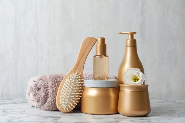 foto de potes de produtos para cabelo ao lado de escova de madeira e toalhas
