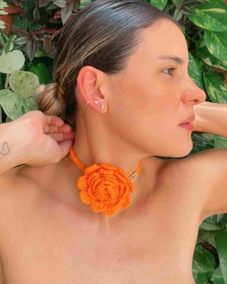 mulher com choker de flor de tricô laranja no pescoço