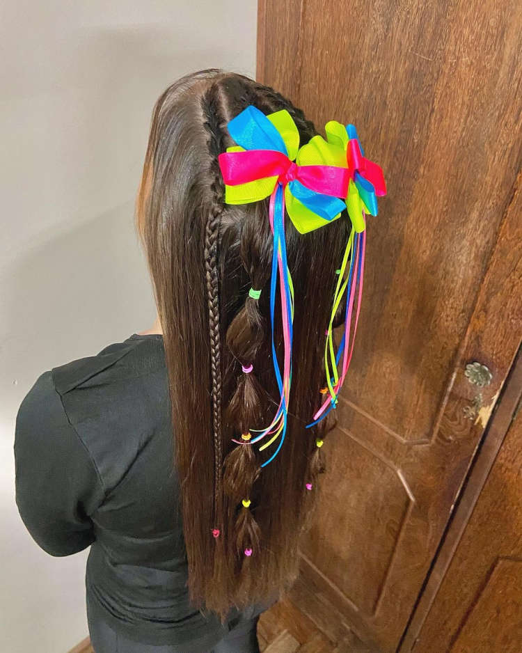 dois laços coloridos com fitas em cabelo castanho