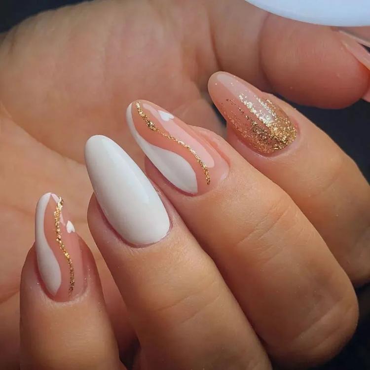 Tipos de alongamentos de unhas: unhas de fibra de vidro, decoradas com glitter dourado e esmaltação nas cores bege e branco