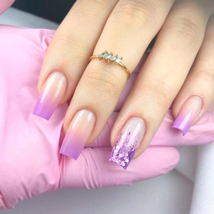 Tipos de alongamentos de unhas: unhas em gel, decoradas com glitter e esmaltação na cor lilás. 