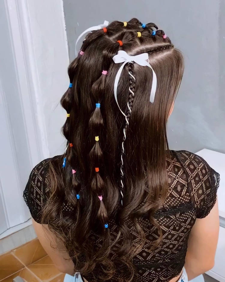 Penteado de festa junina em cabelo castanho, com tranças e fitas brancas.
