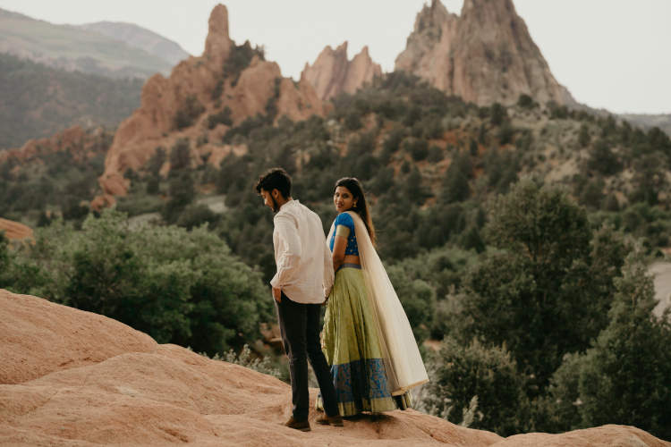Foto de um casal de pé em uma colina rochosa