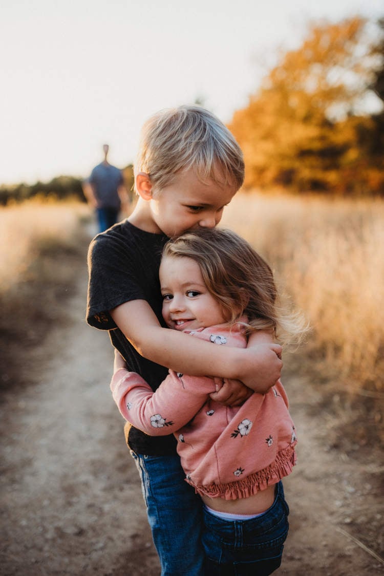 uma menina e um menino se abraçando em um campo.