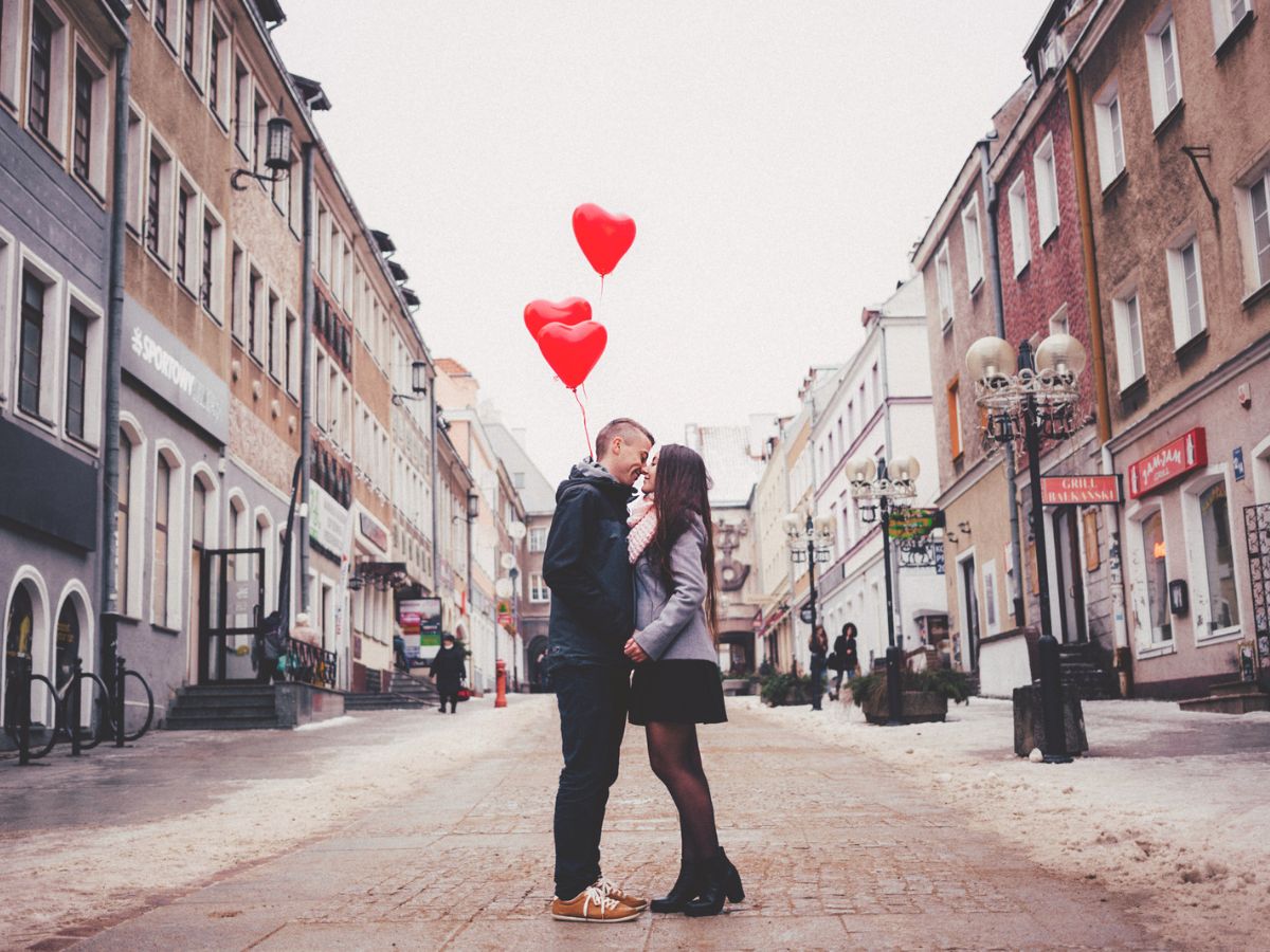 Casal com balões de coração em rua de cidade