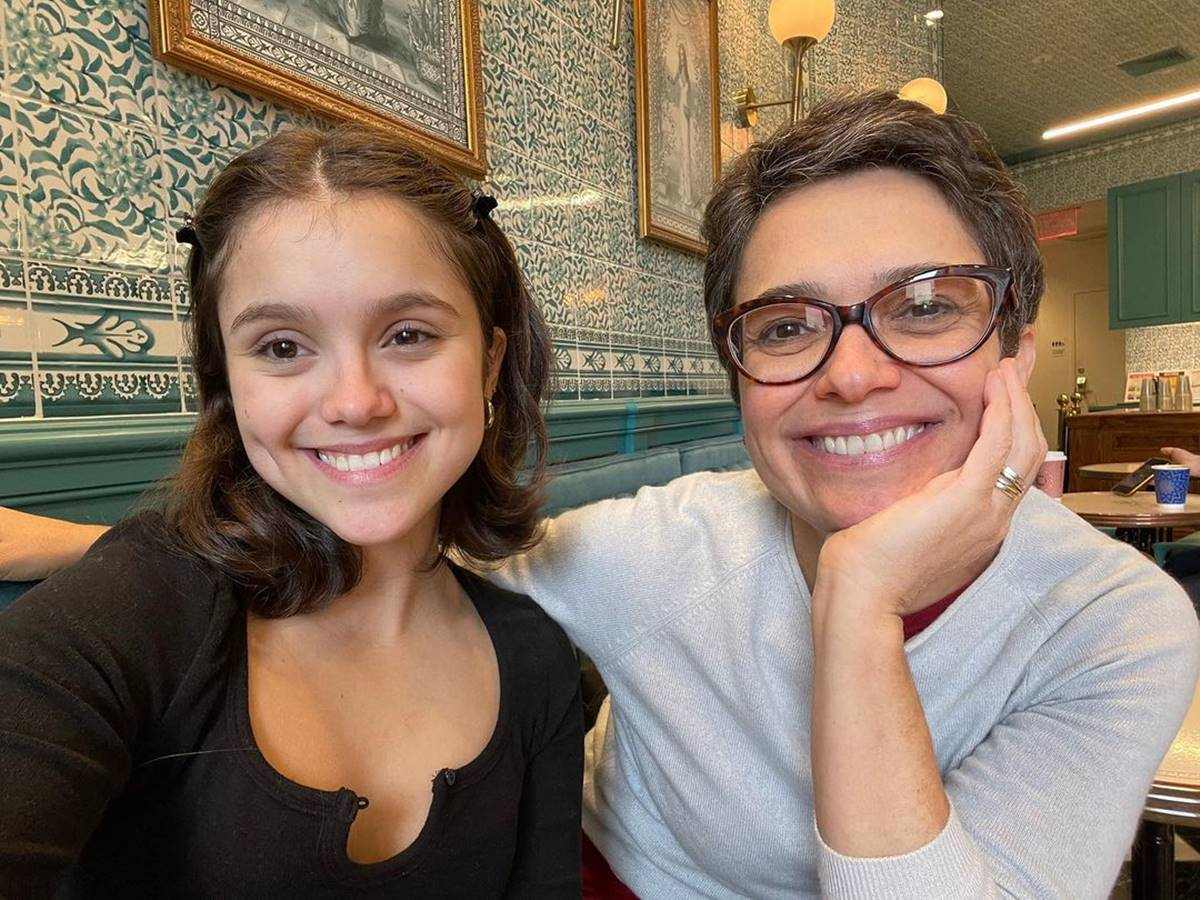 Filha de Sandra Annenberg e a jornalista sentadas em restaurante com decoração verde.