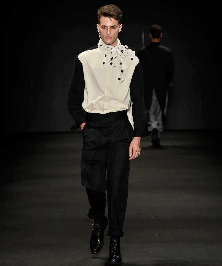 Modelo com camisa preto e branca, calça social e lenço de bolinhas no pescoço