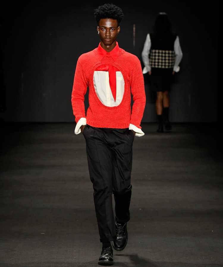 Modelo com casaco vermelho com círculo no meio e calças